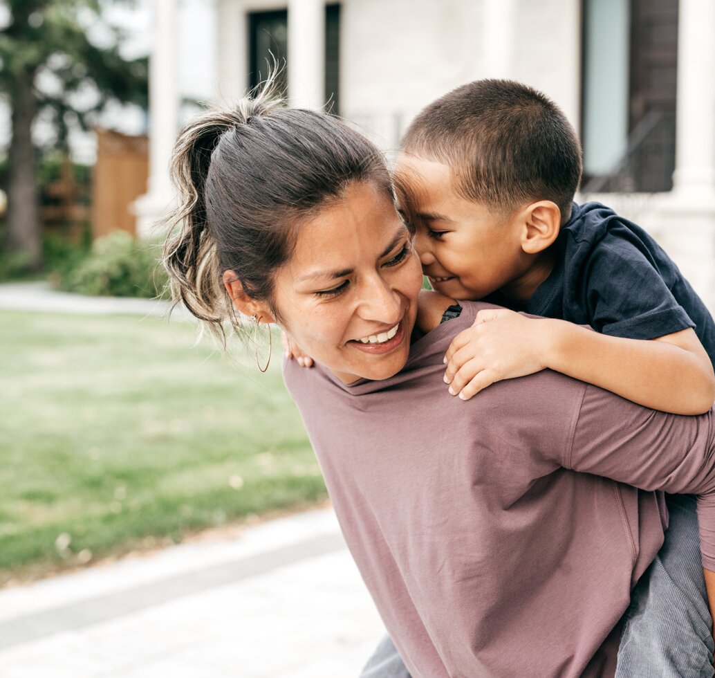 Mother smiling holding a child on her back