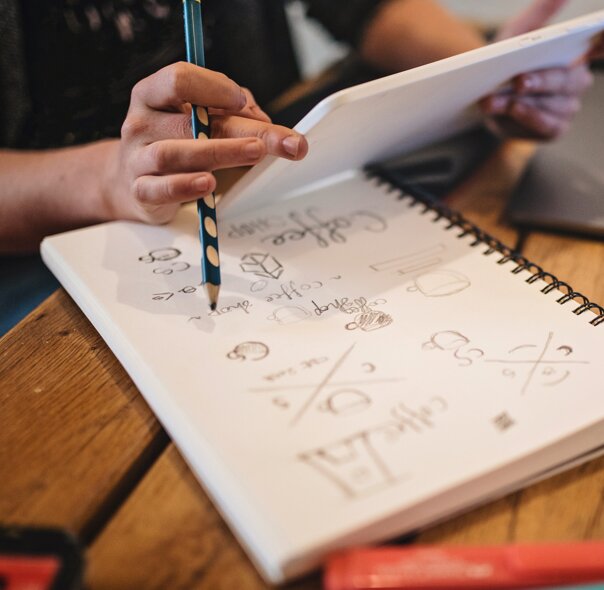 A hand with a pencil and notebook