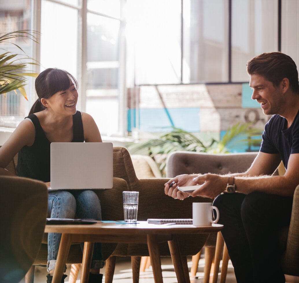 Woman and man sitting by a coffee table laughing